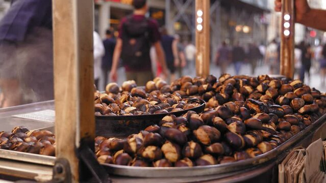 Famous Cheapest Turkish Street Food. grilled roasted chestnuts in trolley in Istanbul. Macro photography. Seller frying and selling in bag in tourist place.