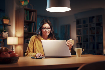 Happy woman using her laptop at night