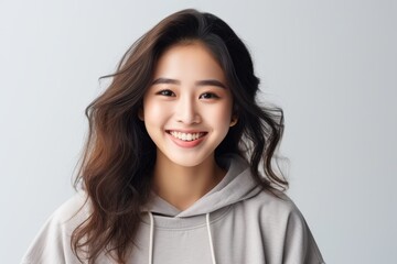 Fototapeta premium Portrait of a smiling young Asian woman with flowing hair on a light background.