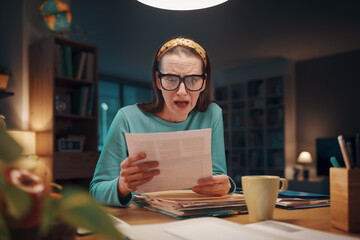 Fototapeta premium Shocked woman checking invoices at home