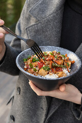 Woman eating tasty rice, meat and vegetables with fork, closeup