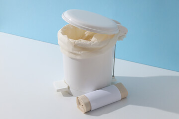 Garbage can and roll of garbage bag on blue background