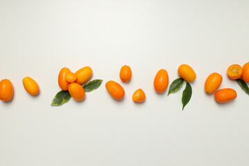 Kumquat and leaves on wooden background, top view