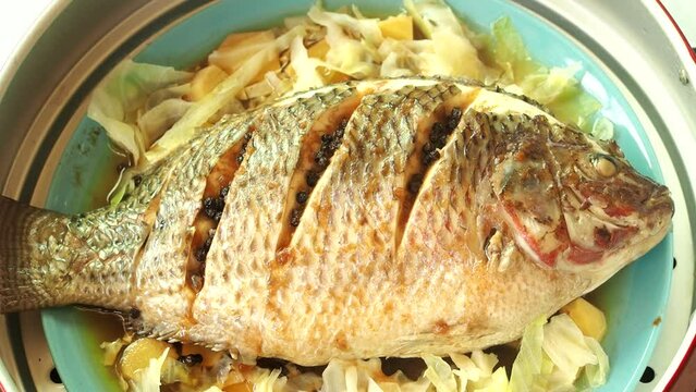 Steaming  tilapia fish with herbs in pot, Thai famous food.