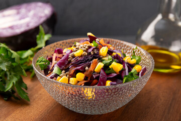  Fresh salad with red cabbage, carrots, hemp seeds and corn in a bowl on the table