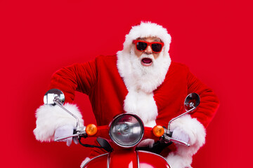 Portrait of crazy impressed santa claus drive fast bike hurry new year time isolated on bright red...
