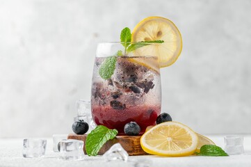 Pitcher of freshly prepared blueberry mojito cocktail garnished with colorful fruit pieces.