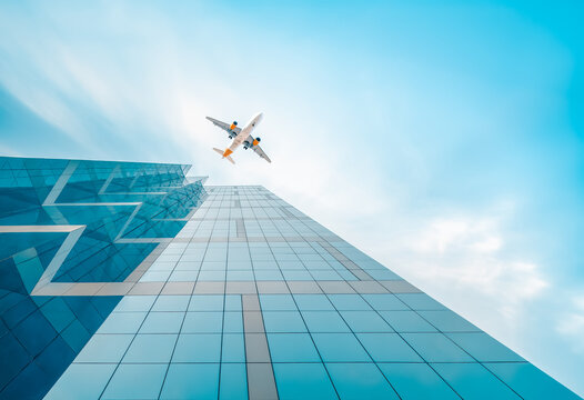Airplane flying over glass skyscrapers of financial district - Abstract cityscape background. - Powered by Adobe
