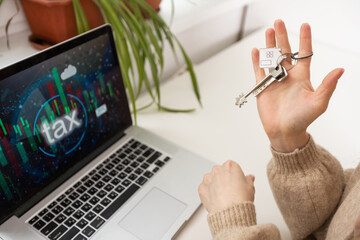 Woman holding keys with laptop and taxes