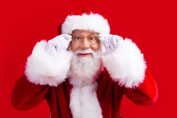 Photo of funky senior new year santa claus wear white gloves eye glasses looking empty space isolated on red color background