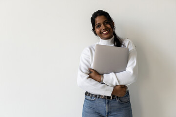 Pretty Indian young woman using laptop standing against white background