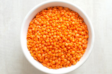 Fototapeta na wymiar Orange lentils in a white bowl on a light background. The concept of proper nutrition. Vegan and vegetarian food. Horizontal orientation. Top view