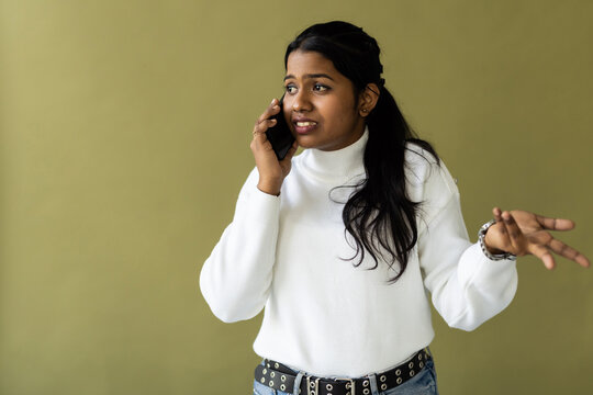 Indian woman talking on cellphone on green background