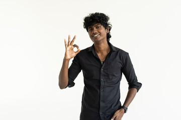 Young indian manstanding over isolated white background smiling positive doing ok sign with hand and fingers