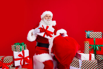Photo of nice senior man saint nicholas packing giftboxes preparing new year holidays magic night isolated on red color background