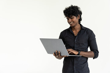 Confident young Indian man holding laptop and smiling while standing against white background