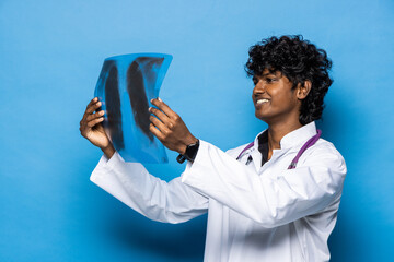 Indian doctor in blue uniform looking at x-ray scan image of spine