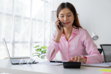 Young Asian woman, secretary, business consultant, sales manager talking on the phone in the office and business background, tax, accounting, statistics and analytical research concept.
