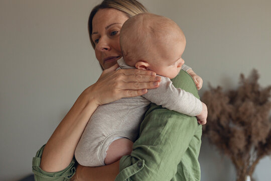 Mother comforting burping baby over shoulder