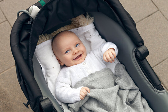 Happy smiling baby boy lying in stroller looking up