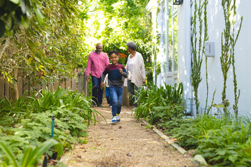 Happy african american boy running in sunny garden in backyard, copy space