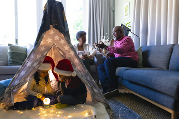 African american grandparents and grandchildren discussing and looking at snow globe at home