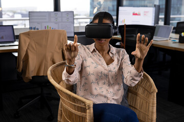 Happy african american casual businesswoman in vr headset using virtual interface in office