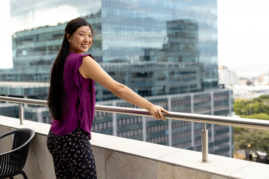Portrait of happy asian casual businesswoman standing on outside terrace at office, copy space