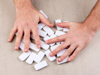 male hands shuffle inverted white dice of domino board game on gray background top view close-up - 678088303