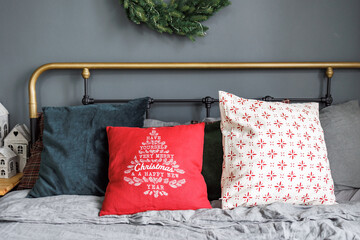 Comfortable metal bed with bright pillows in a red shade in a bedroom decorated for Christmas...