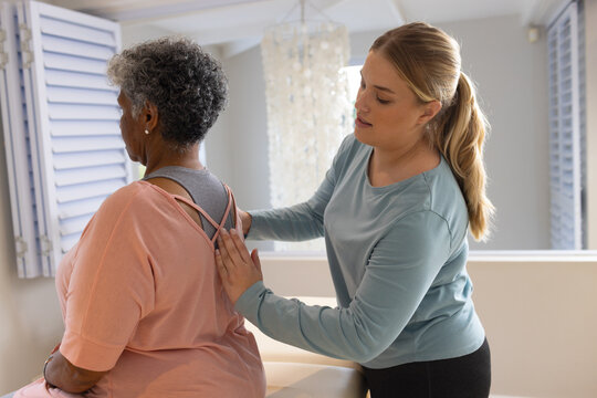 Caucasian female physiotherapist massaging senior african american female patient, copy space