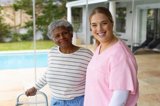 Happy caucasian female nurse and senior african american female patient by window