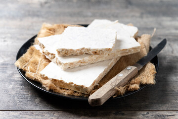 Traditional Christmas sweet, pieces of delicious almond nougat on wooden table	