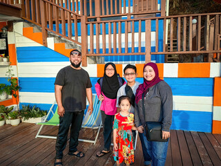 Malay Muslim family taking photo while traveling on vacation at a beach resort in Malaysia.