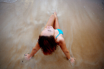 A beautiful girl in a bikini on a wild beach, bathing in the clear waves of the warm sea. a heavenly place and a beautiful model.