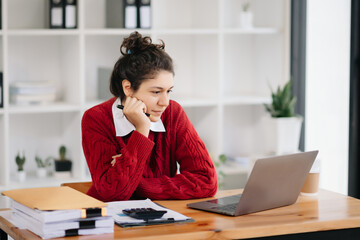 Beautiful woman using laptop and tablet while sitting at her working place. Concentrated ..