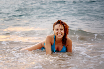 A beautiful girl in a bikini on a wild beach, bathing in the clear waves of the warm sea. a heavenly place and a beautiful model.