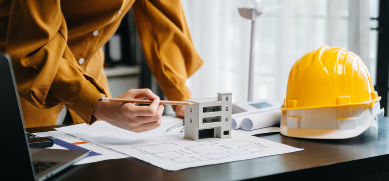 Close Up Of Business People Having Consultation About Wind Energy At Company Office. On Architectural Project Site And Making Model House. Asian Industry Professional