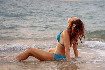 A beautiful girl in a bikini on a wild beach, bathing in the clear waves of the warm sea. a heavenly place and a beautiful model.