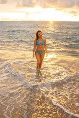 A beautiful girl in a bikini on a wild beach, bathing in the clear waves of the warm sea. a heavenly place and a beautiful model.