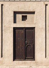 Old stone Arabic building with a brown wooden door. Entrance to traditional Arab house in old Dubai