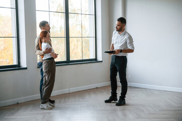 Empty room. Realtor shows an apartment to a young couple