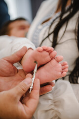 Baptism ceremony of a baby. Closeup of tiny baby feet, the sacrament of baptism. Godmother holds...