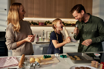 Caucasian family of three making gingerbreads in domestic kitchen