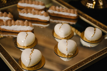 Candy bar on wedding banquet, birthday party, baptism closeup. Pastries with cream on a golden plate. Delicious reception luxury ceremony. Table with sweets, candies, dessert. Side view.