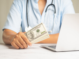 A doctor holding US dollar bills for medical expenses.