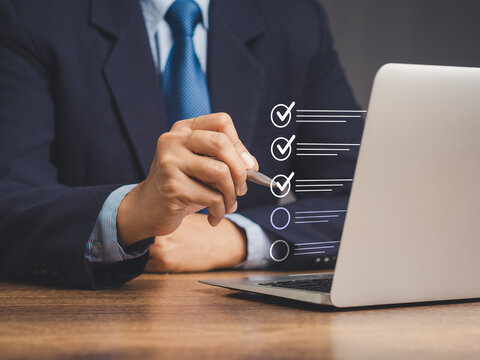 Businessman using a pen to tick the correct sign mark on a virtual screen checklist.