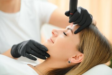 Process of creating permanent brow makeup with a machine at beauty salon