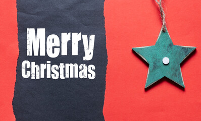 Fototapeta na wymiar MERRY CHRISTMAS words on a black sheet of paper and a red background.. Time for Christmas.