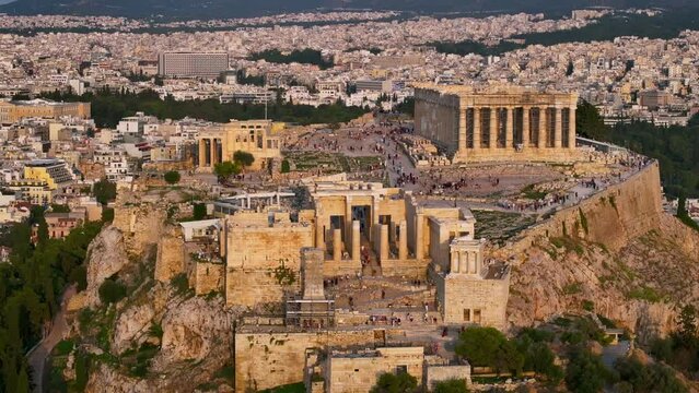 Aerial close-up view of the Acropolis of Athens, Greece, with numerous tourists enjoying the monument during golden sunset time